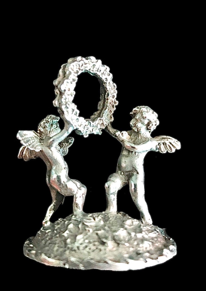 Serie di sei segnaposti in argento con coppia di putti che reggono una ghirlanda. -photo-2