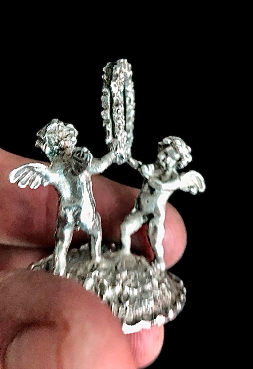 Serie di sei segnaposti in argento con coppia di putti che reggono una ghirlanda. -photo-1