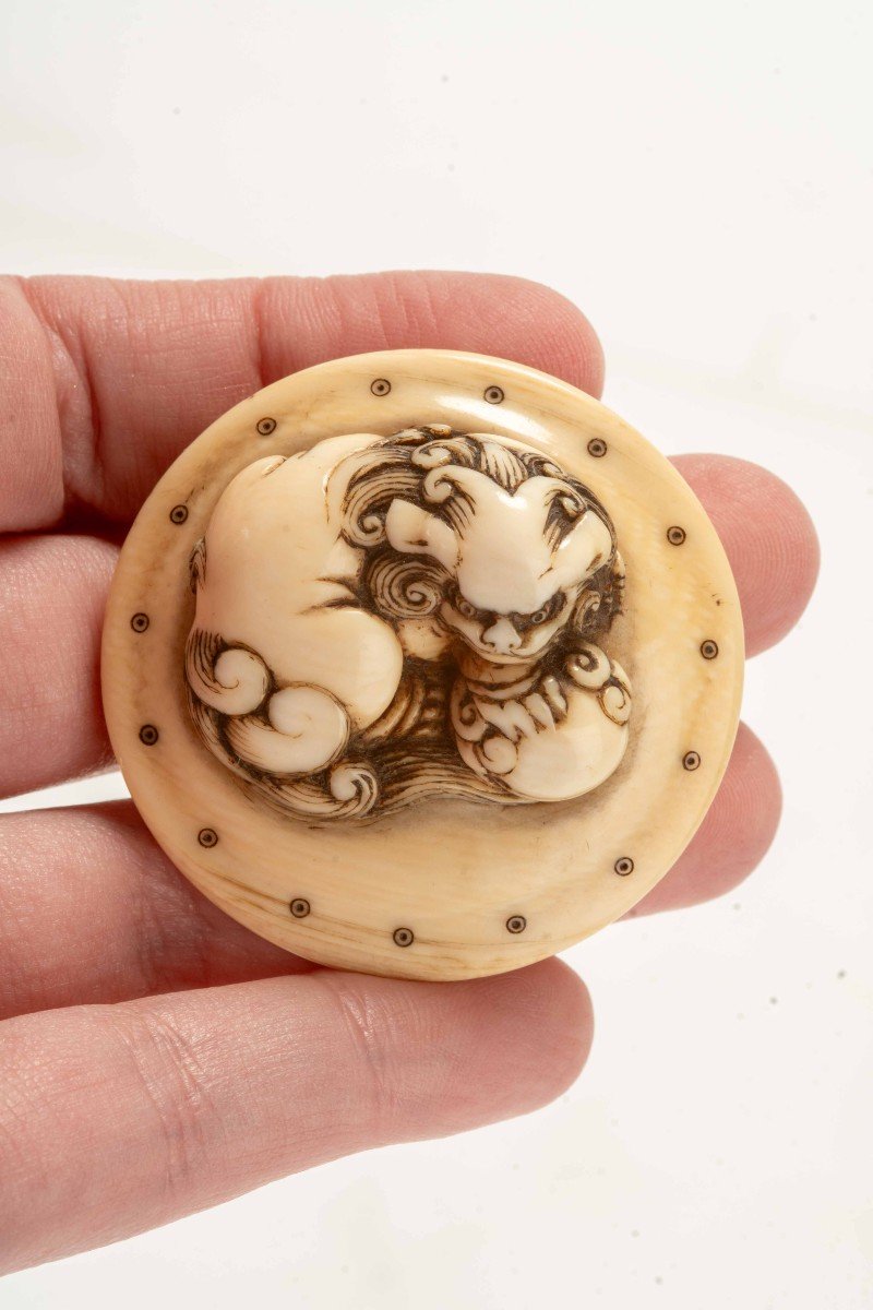 Netsuke in avorio raffigurante uno shishi accovacciato su un tamburo-photo-1